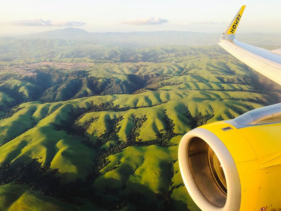 Airplane flying over lush green landscape symbolizing green air travel